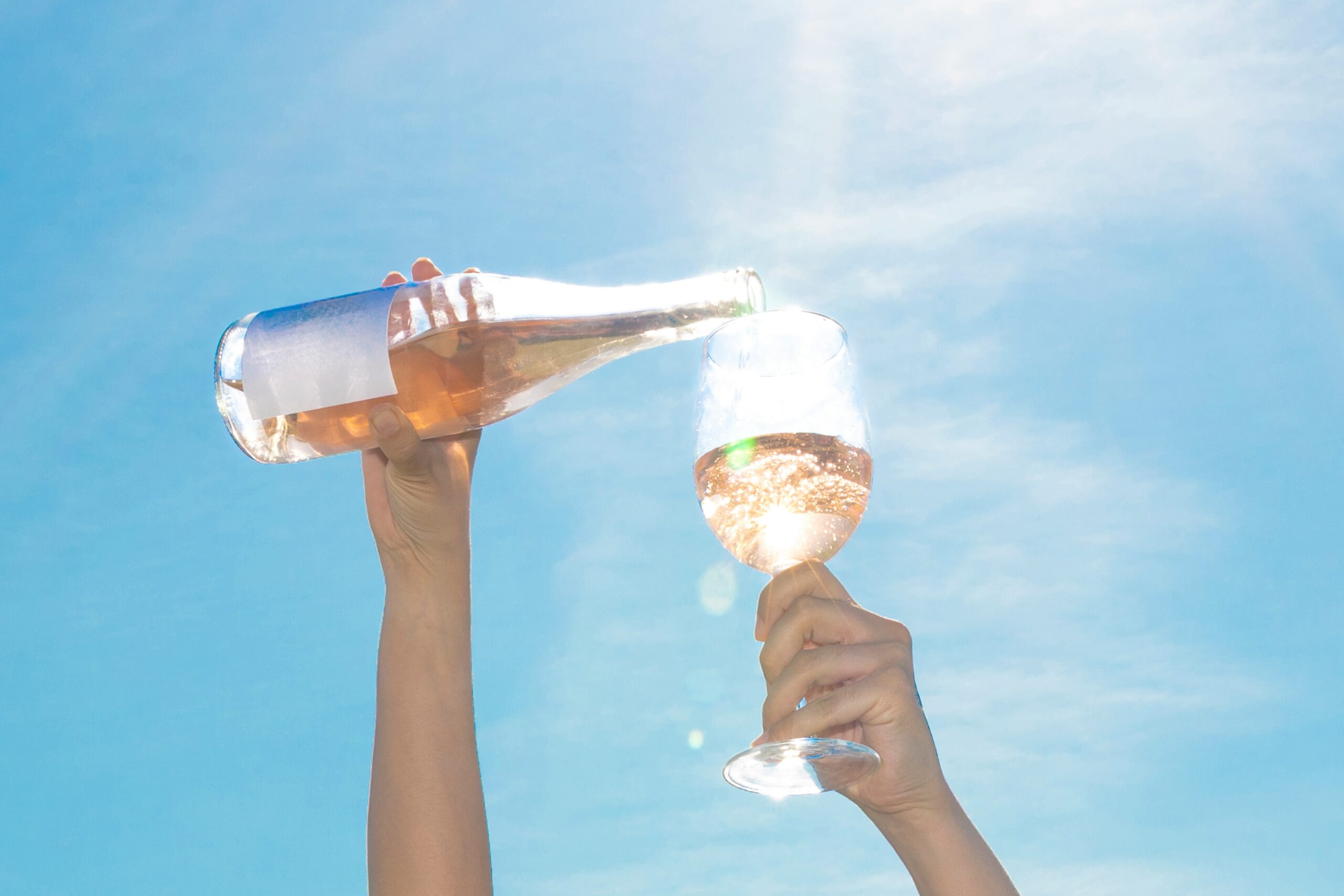 Taça e garrafa de vinho rose ao sol.