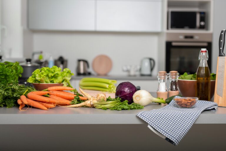 Diversos legumes coloridos e frescos dispostos sobre uma mesa de cozinha limpa e bem iluminada.