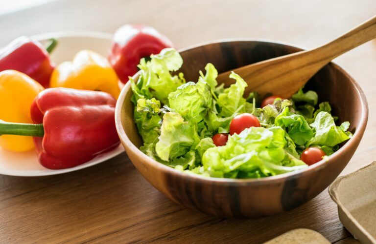 Travessa de salada fresca com folhas de alface e fatias de tomate servida na mesa.