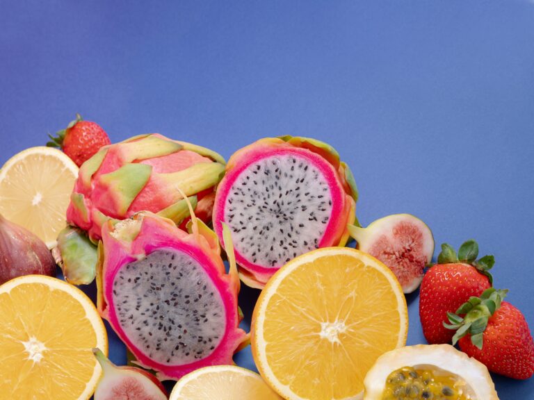 Uma fruteira cheia de frutas variadas em destaque sobre um fundo azul.